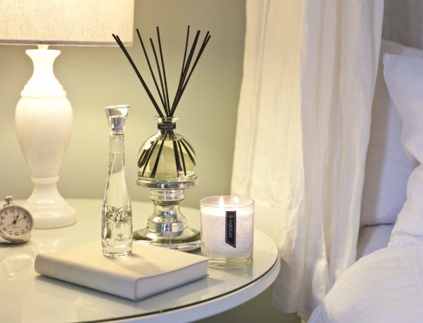 A-bedside-table-with-a-scented-candle-lamp-reed-diffuser-perfume-and-a-journal