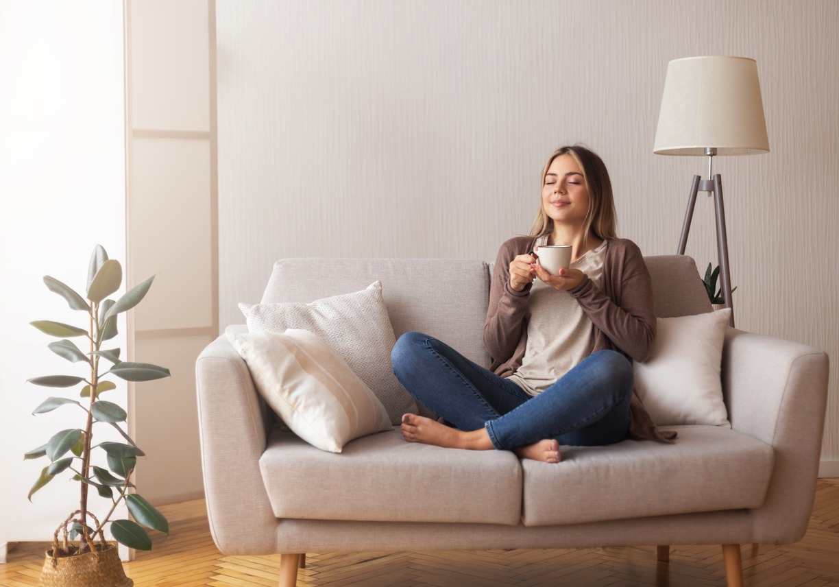 A woman sitting on a couch with a hot drink