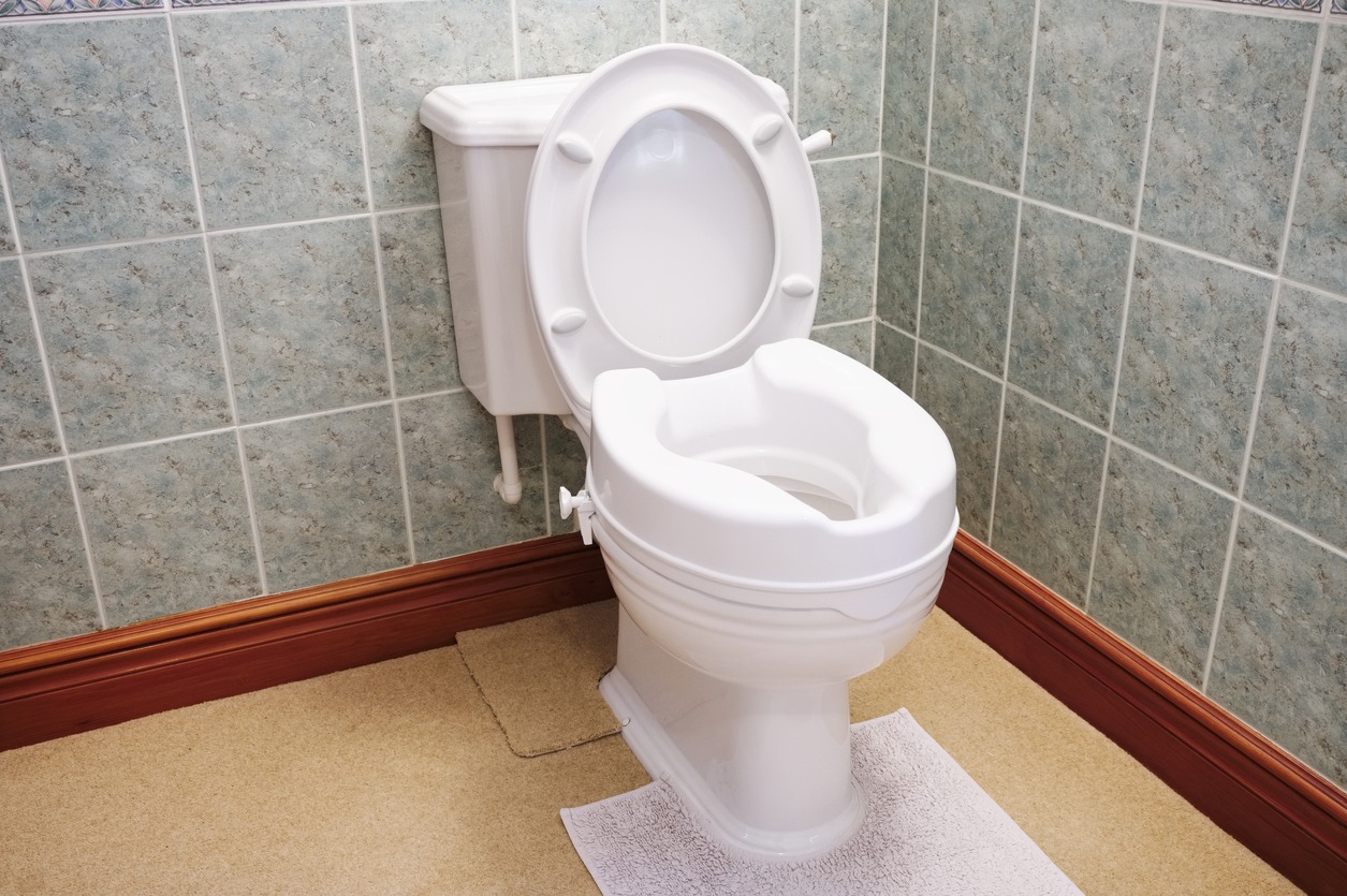 a toilet bowl attached with a raised toilet seat