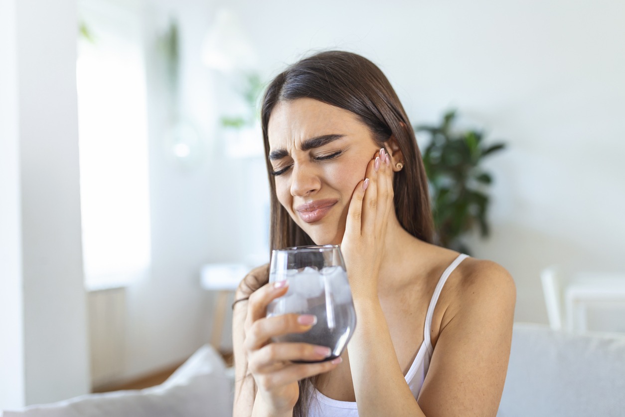 woman feeling tooth pain after drinking cold water