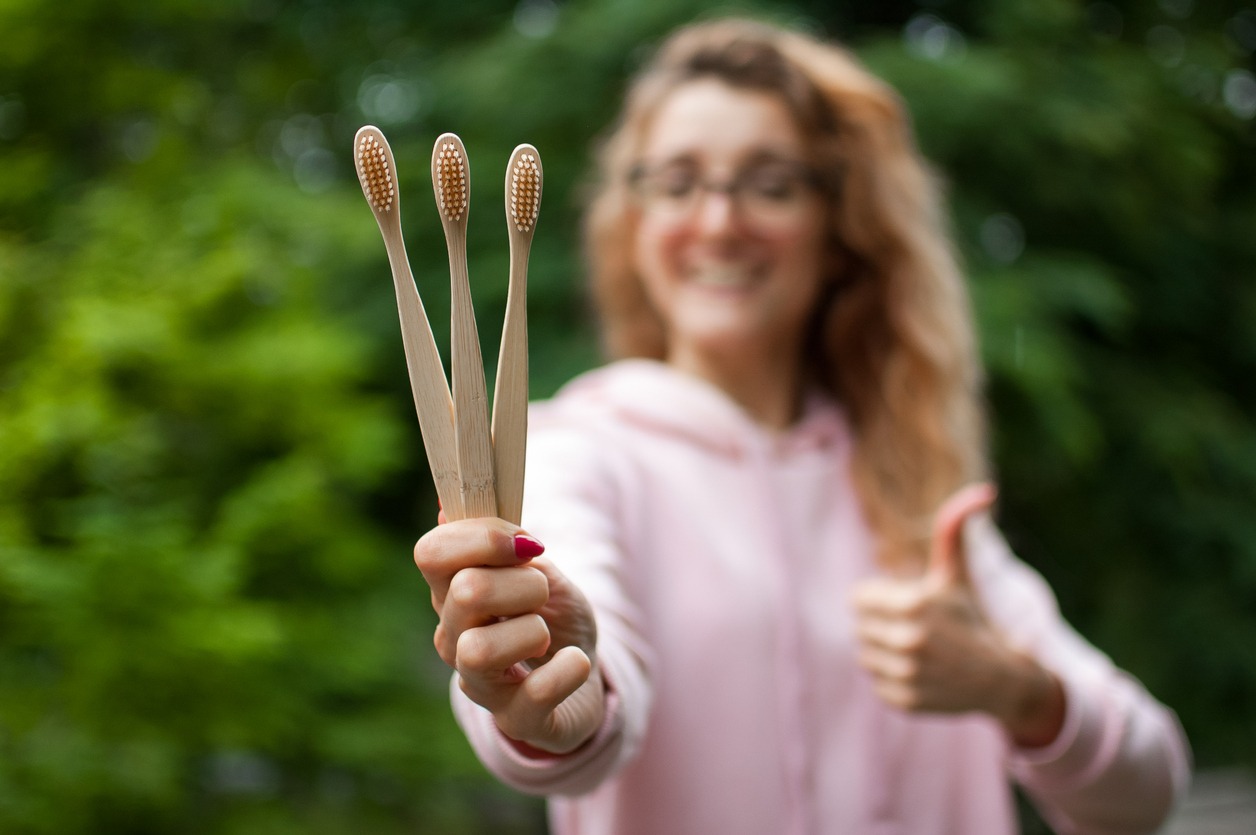 woman holding bamboo toothbrushes