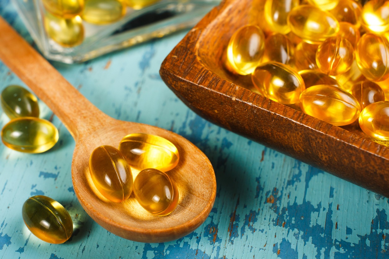 fish oil capsules on wooden spoon