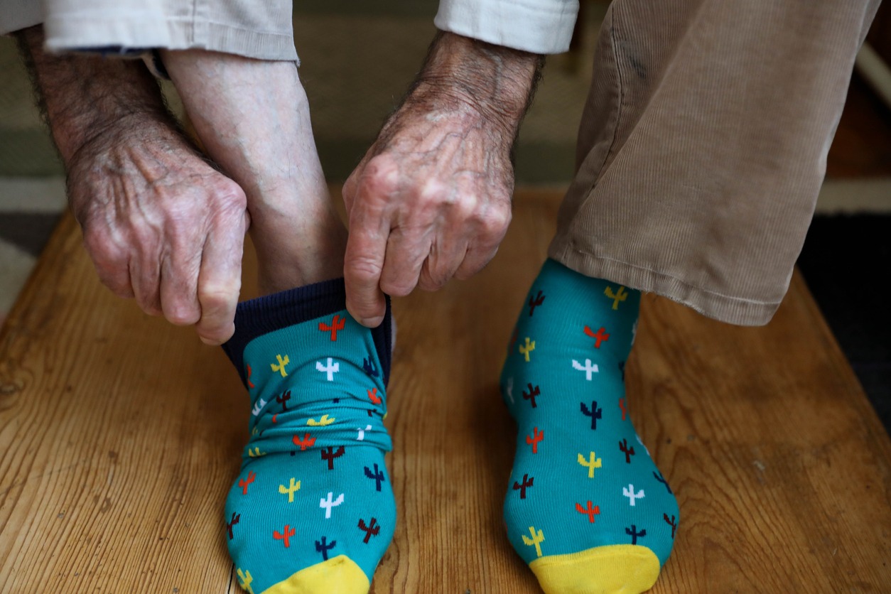 elderly man putting on socks
