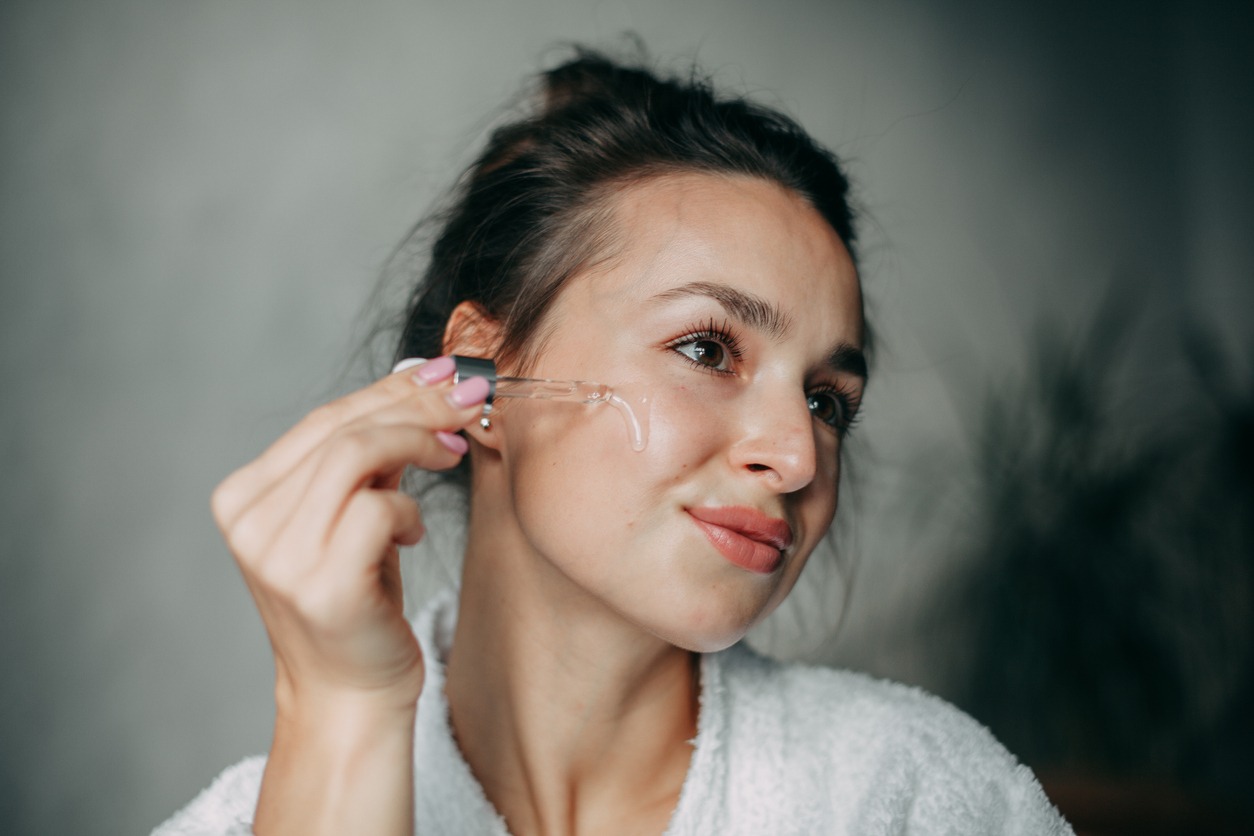 woman applies serum on her face