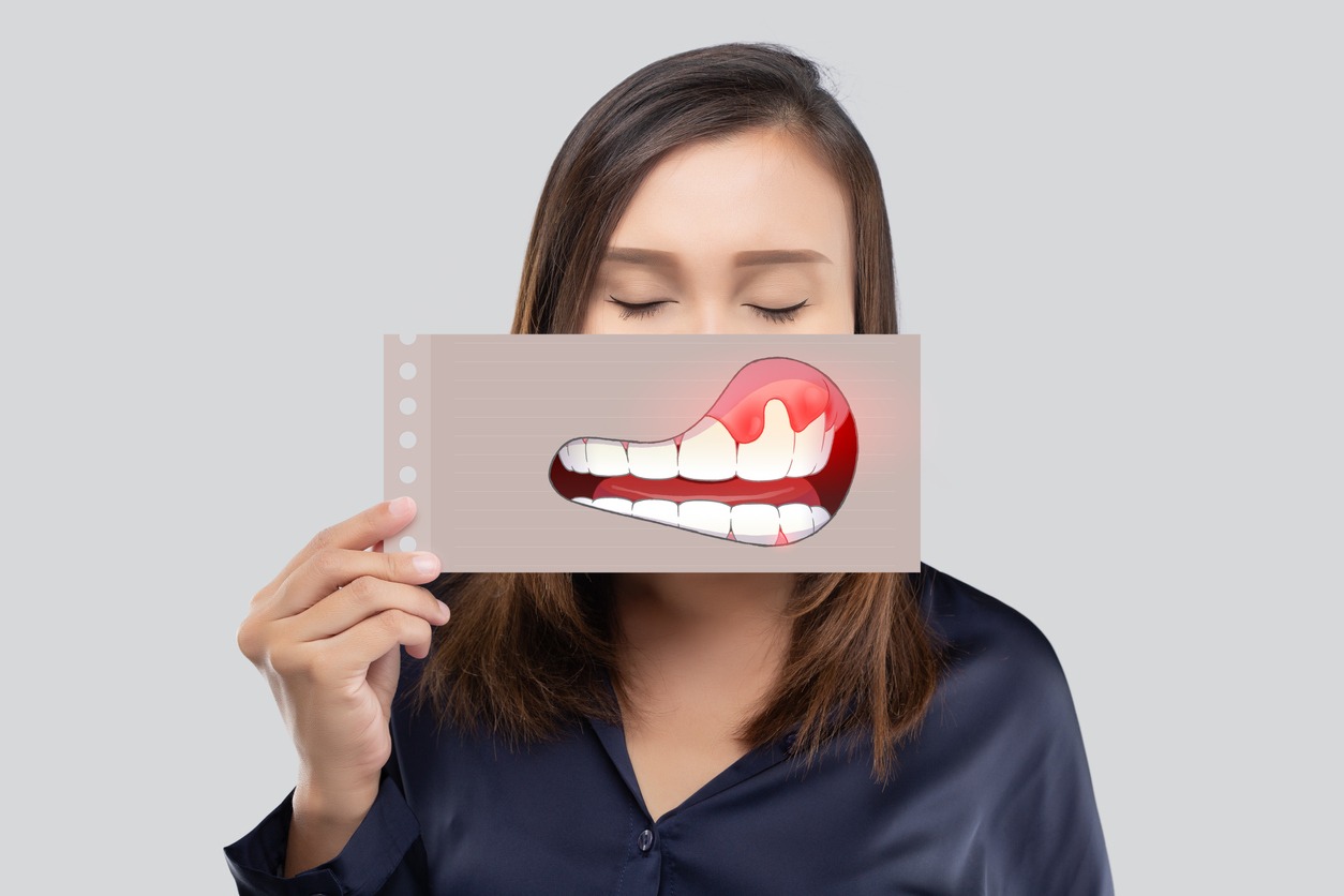 woman holding a paper with an illustration of inflamed and swollen gums