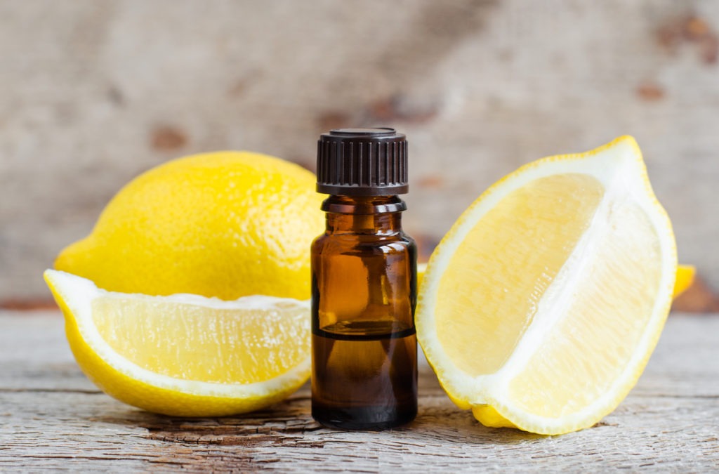 Small bottle of essential lemon oil on the old wooden background. Aromatherapy, spa and herbal medicine ingredients. Copy space