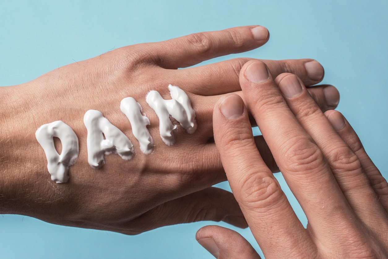 the word pain written on a hand using cream