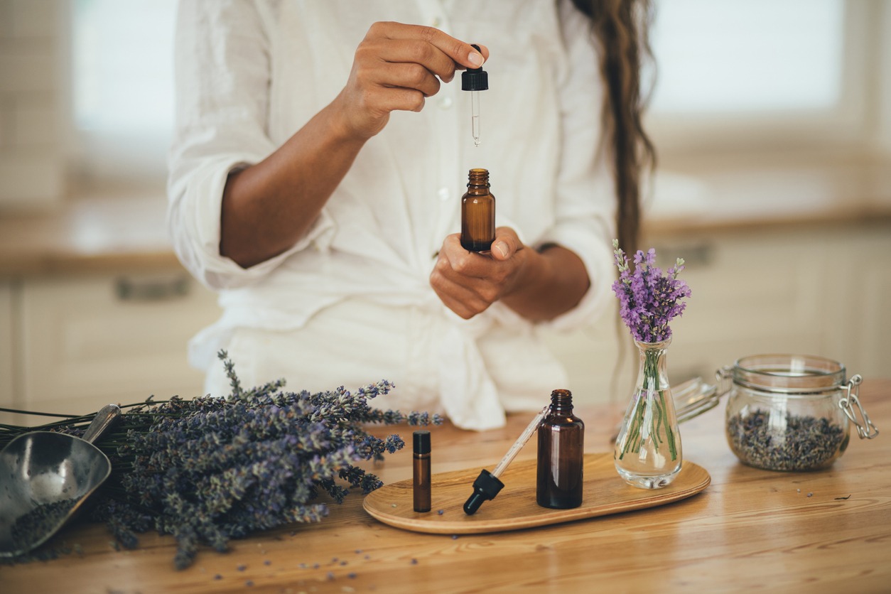 Young woman applying natural organic essential oil on hair and skin. Home spa and beauty rituals