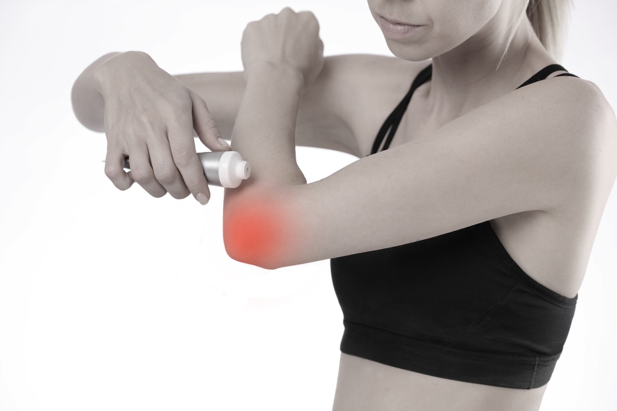 woman applying pain relief cream on her elbow