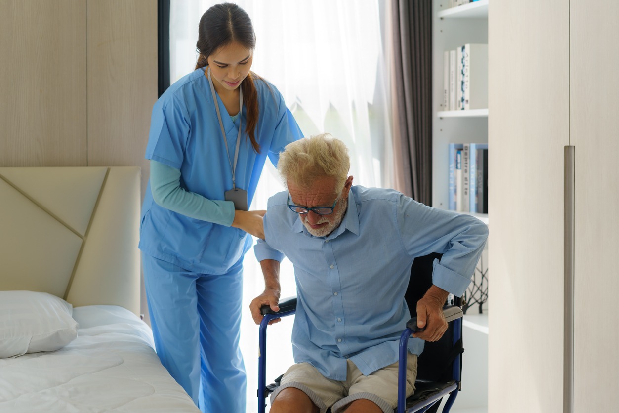 a caregiver assisting a senior man from his wheelchair