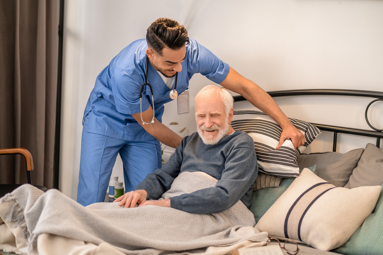 healthcare worker helping a patient change position on the bed