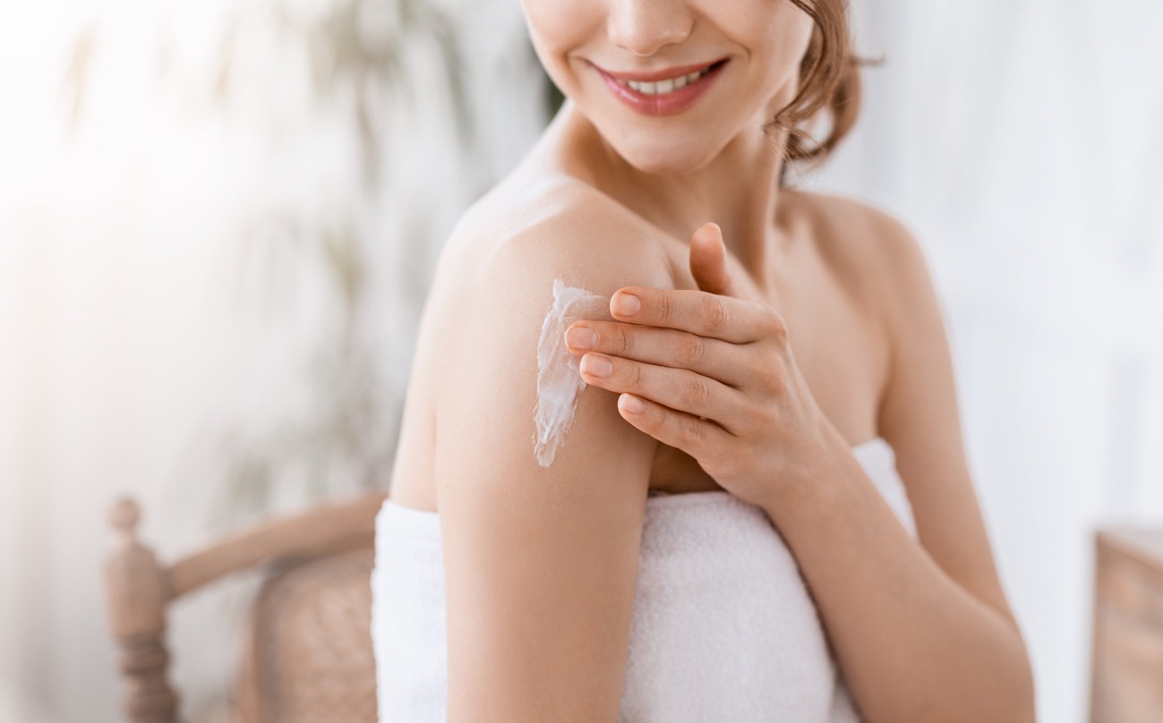 woman applying cream on her shoulder