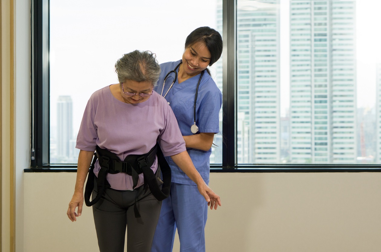 a physical therapist using a gait belt to assist an elderly woman