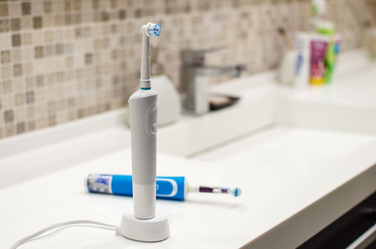 a rechargeable electric toothbrush by the bathroom sink