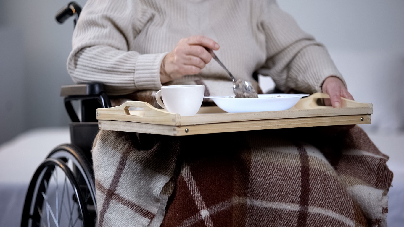 an elderly eating white sitting in a wheelchair
