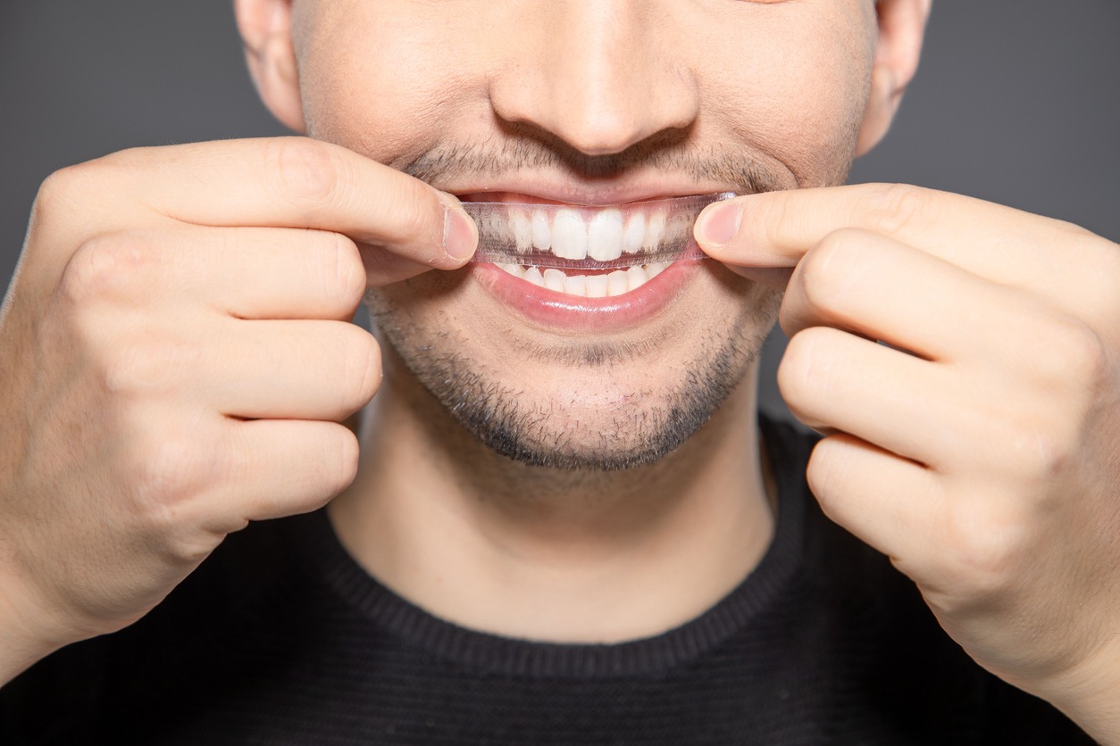 man applying a teeth whitening strip