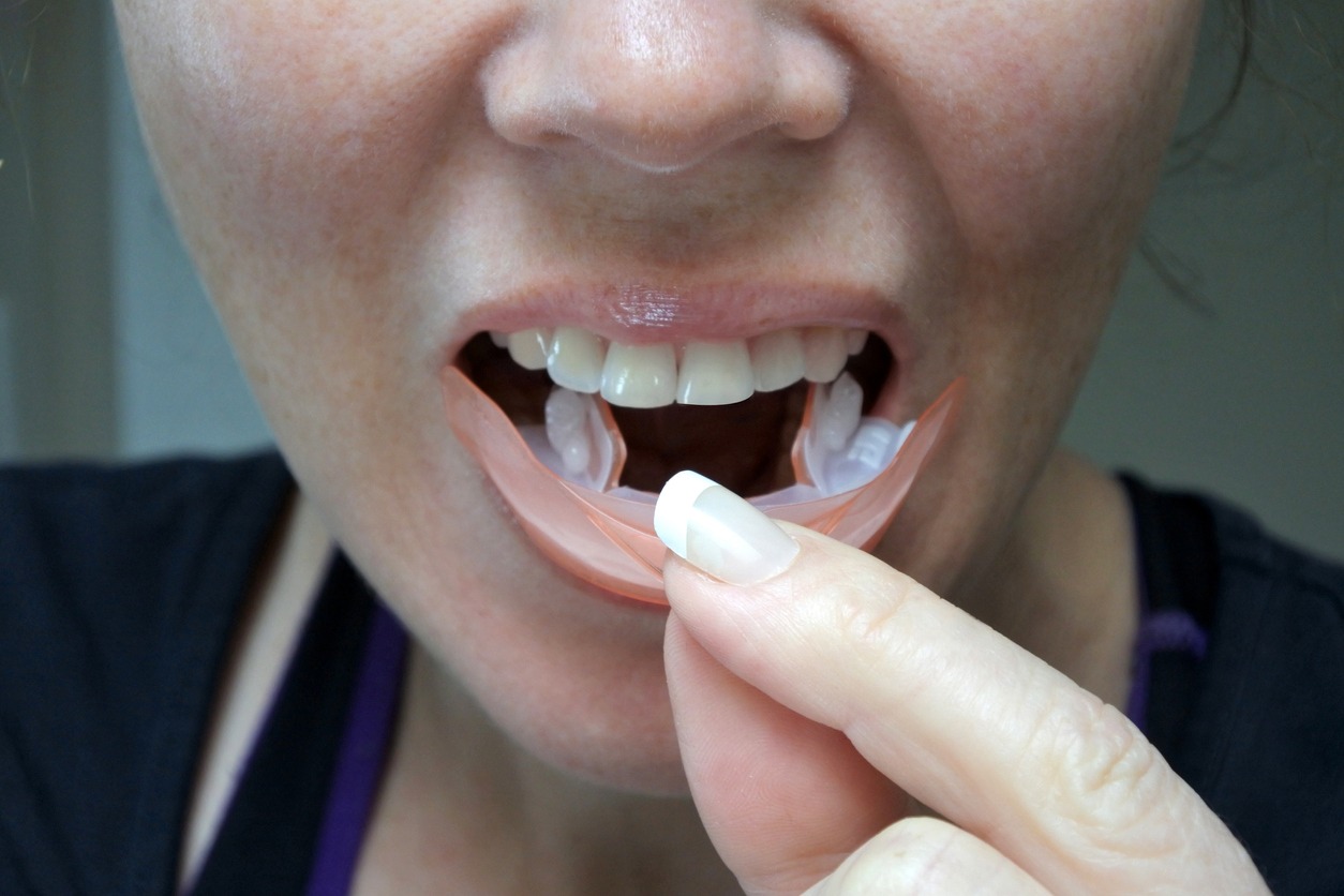woman placing a whitening strip on her teeth