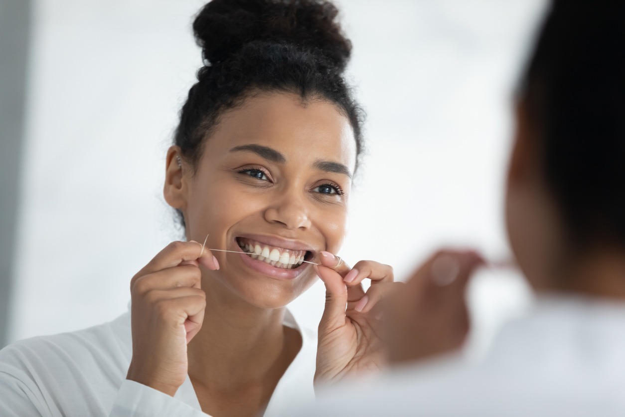 woman smiling while flossing her teeth