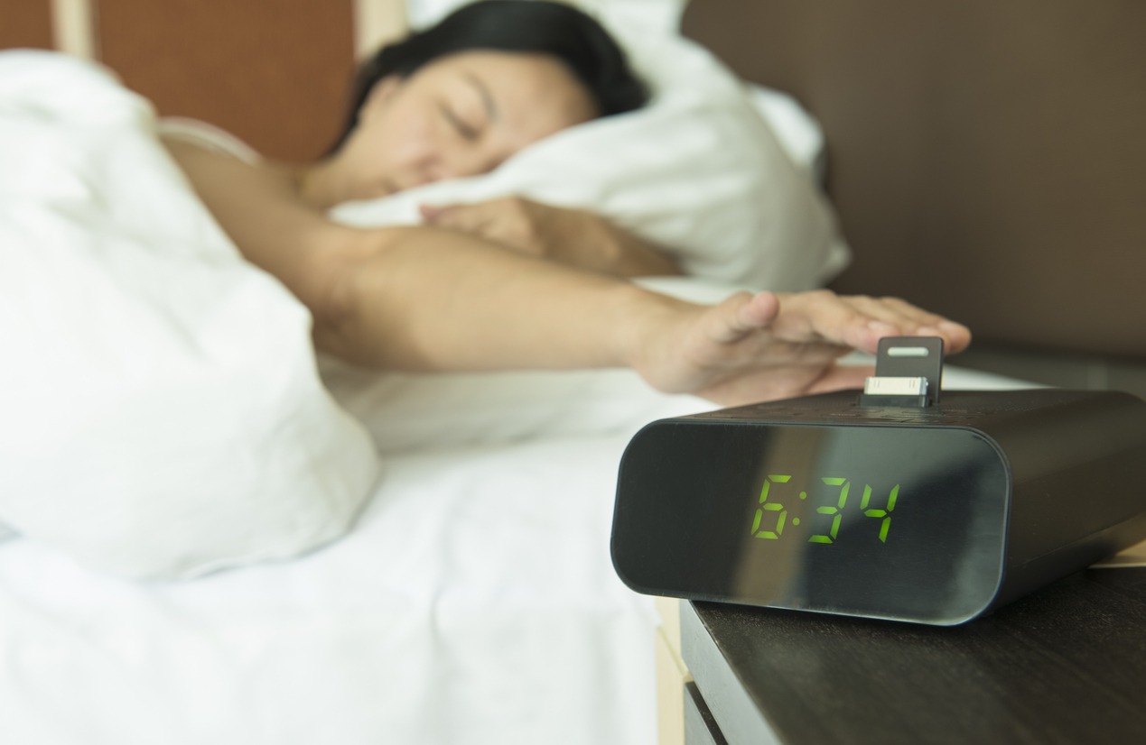 woman turning off an alarm clock