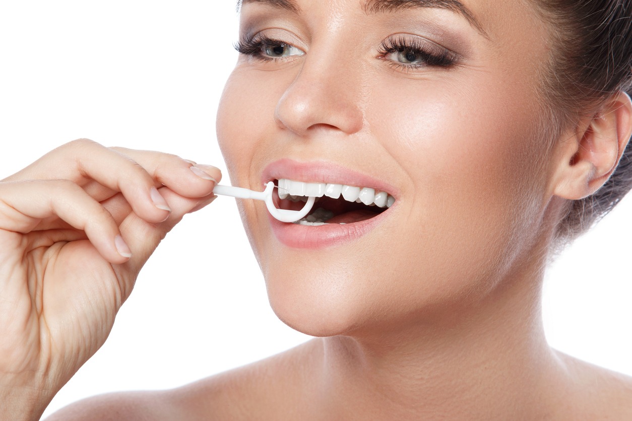woman using a dental floss pick