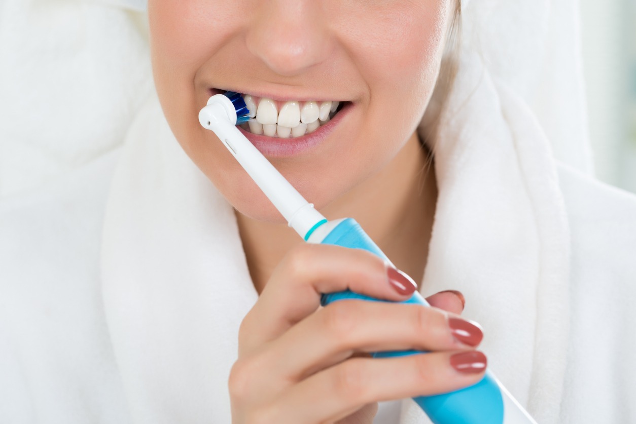 woman using an electric toothbrush