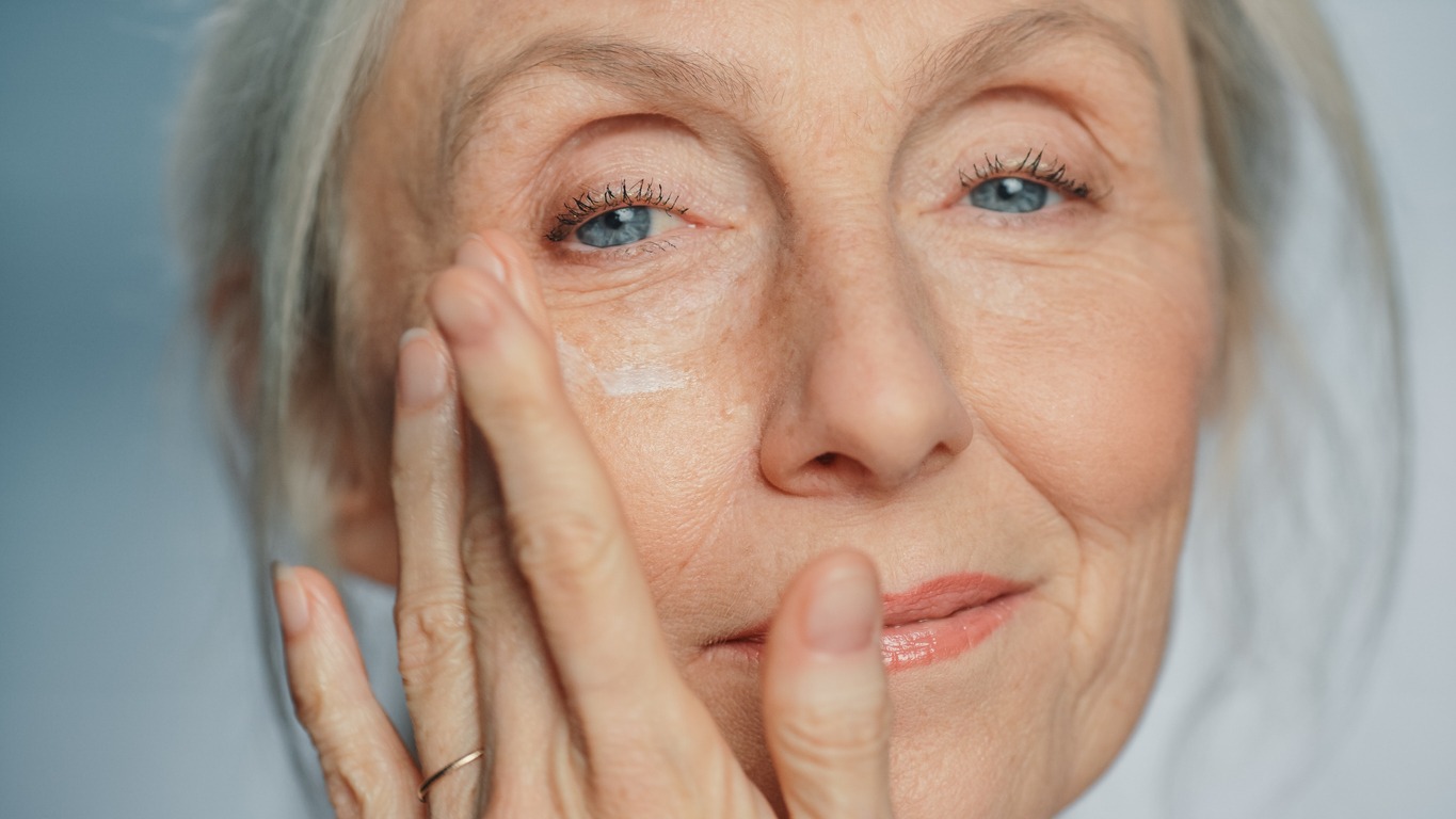 a senior woman applying facial cream