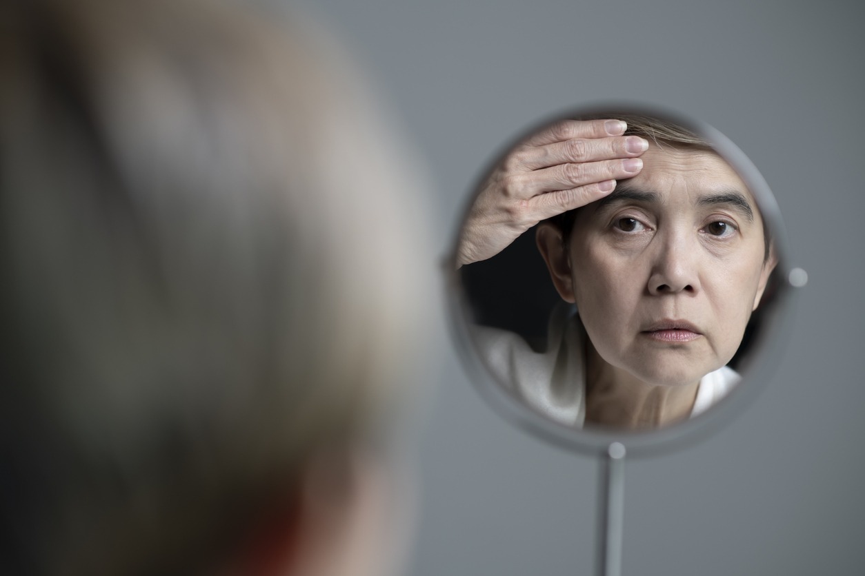 mature woman looking at her mirror reflection