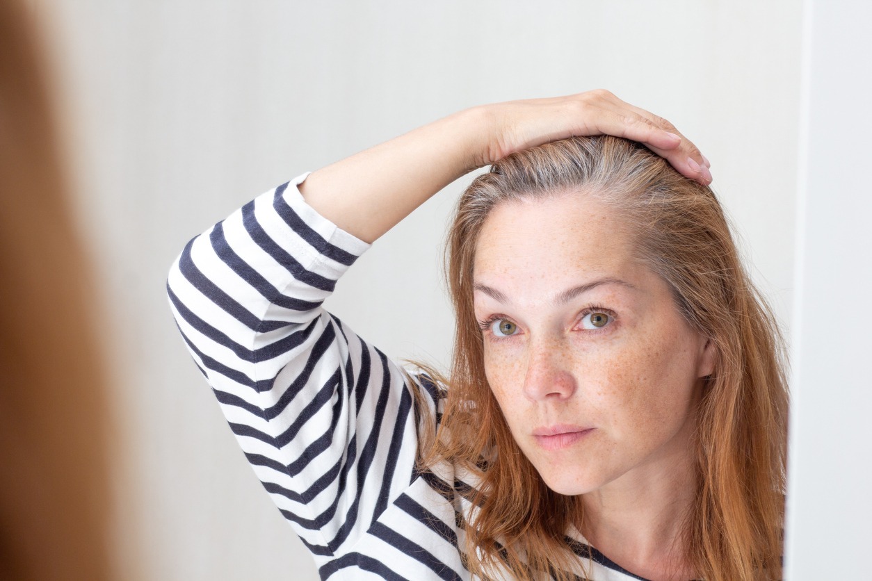 woman looking at her hair that is starting to gray