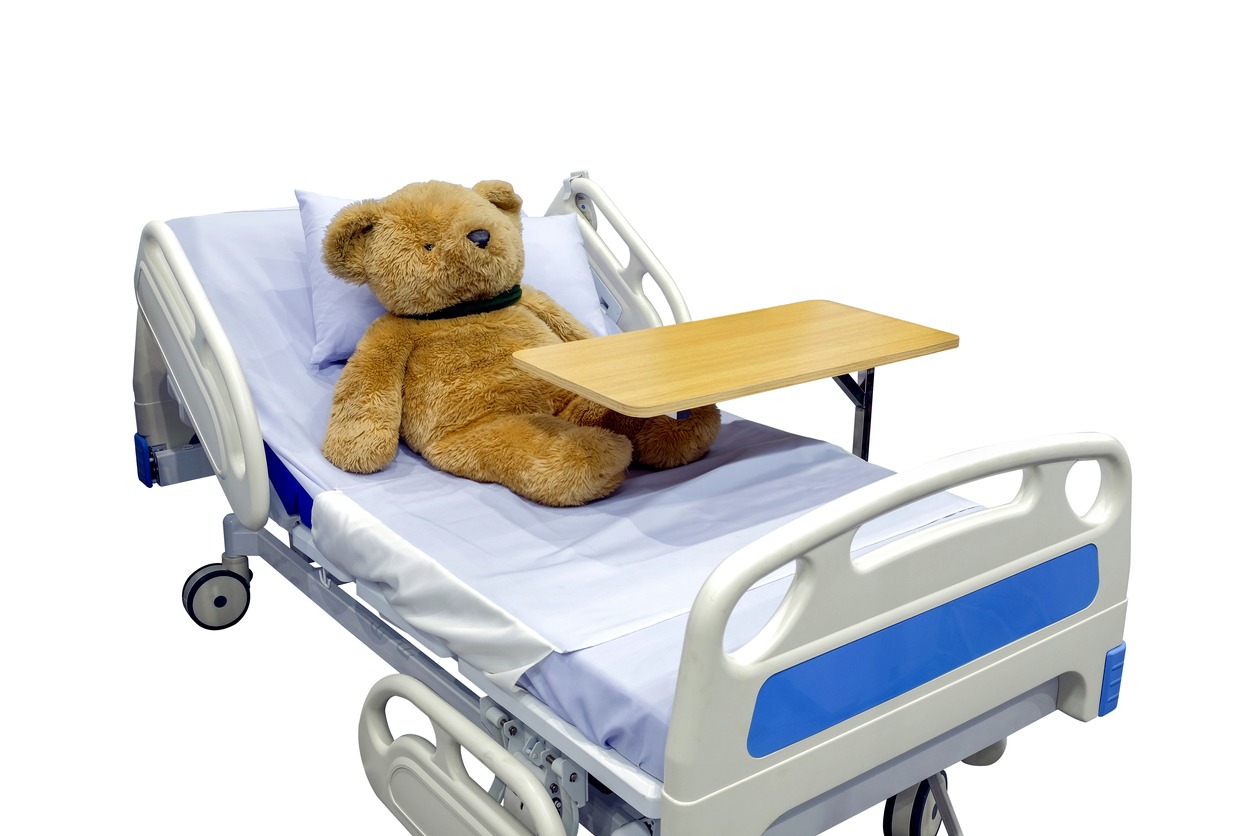 a teddy bear on a hospital bed with an overbed table