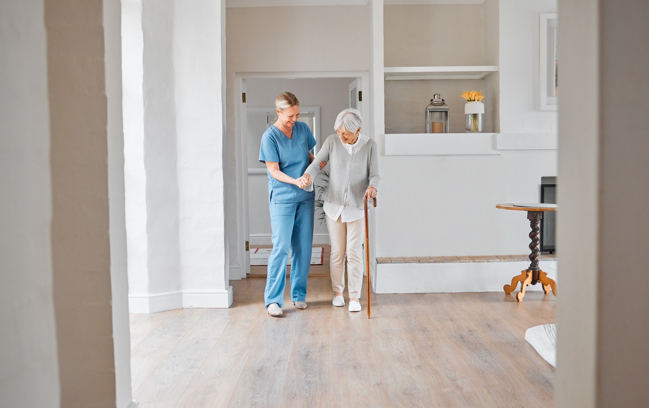 caregiver assisting senior woman using a walking cane