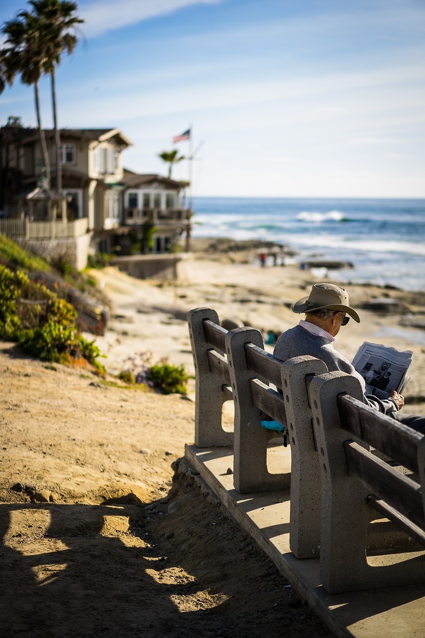 elderly man reading newspaper by the beach 