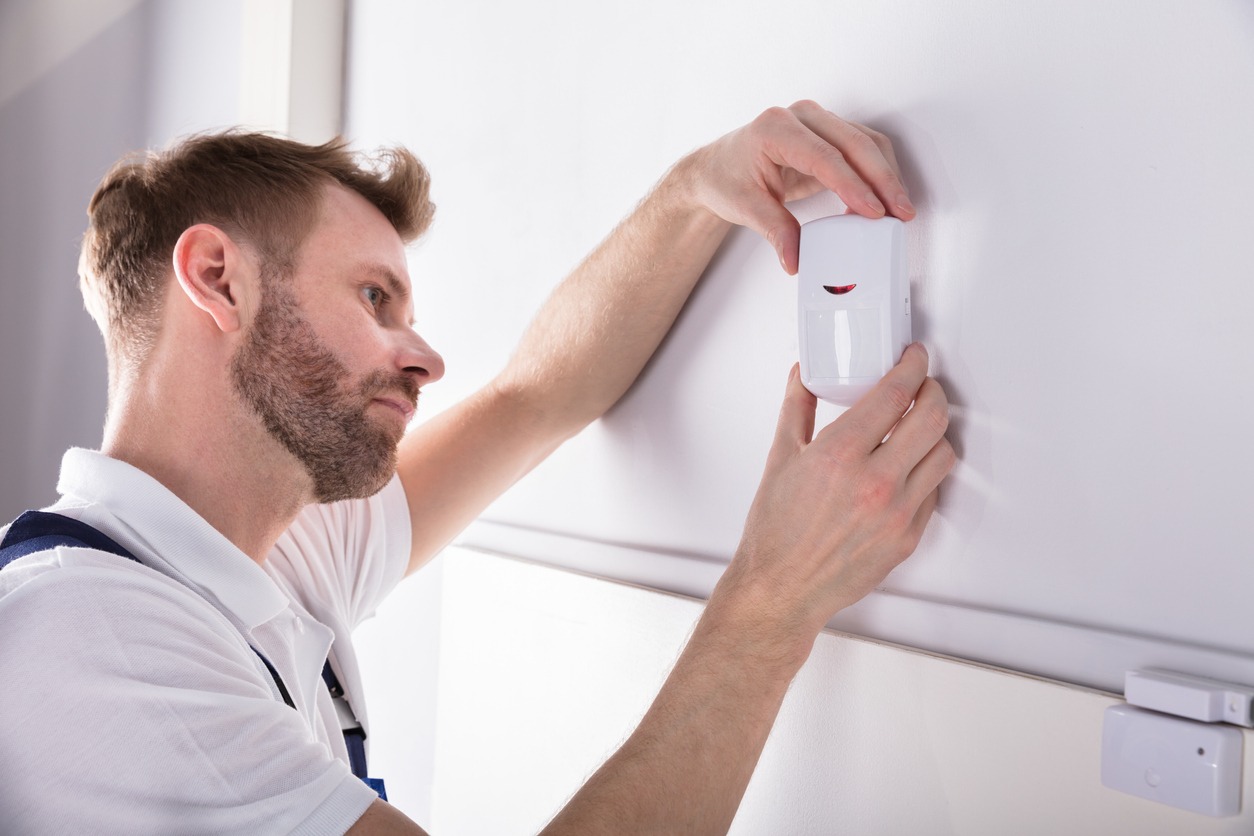 man installing a cordless alarm system on the wall