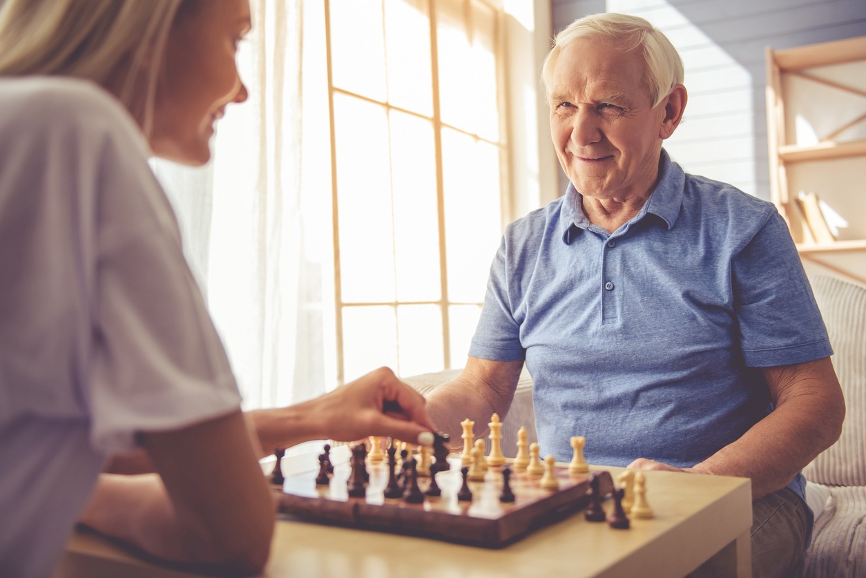 woman and senior man playing chess