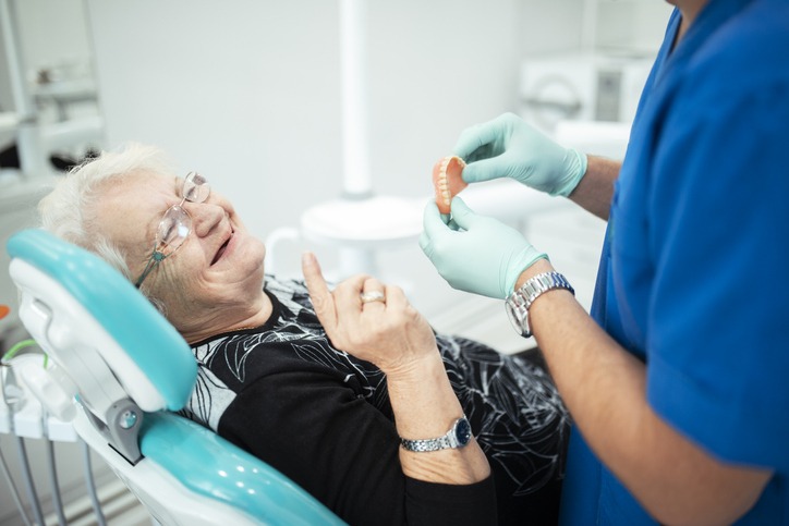 dentist showing senior patient teeth dentures
