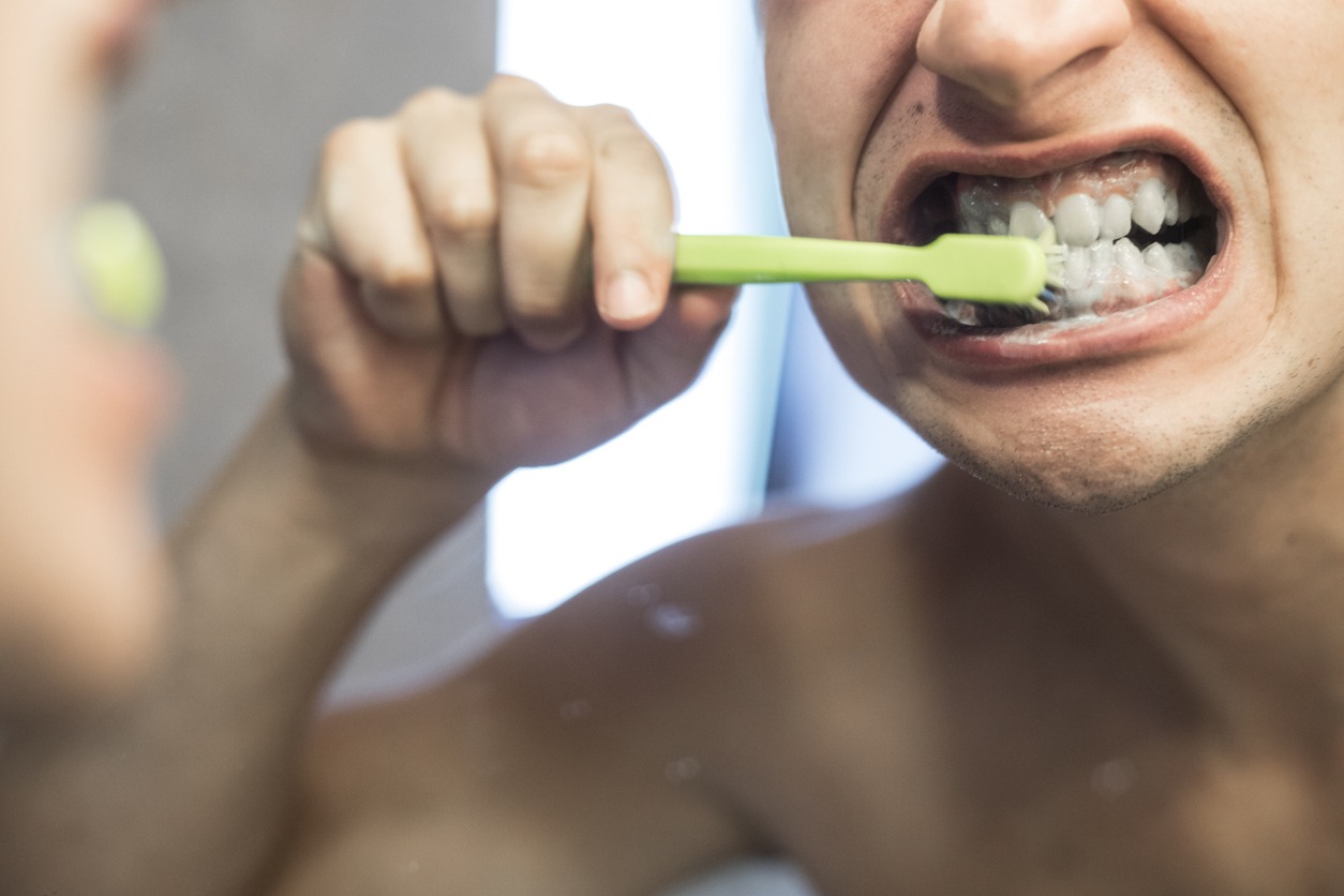 person brushing his teeth hard
