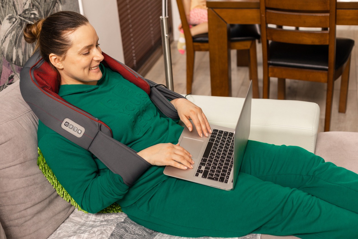 woman using a neck massager at home