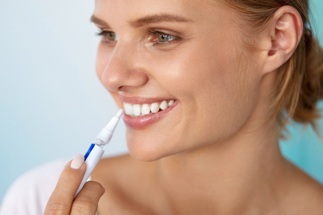woman using a teeth-whitening pen