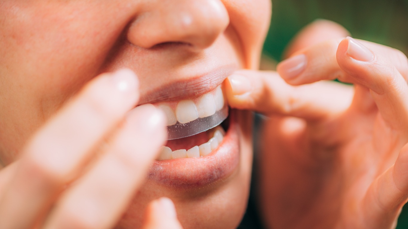 woman using a teeth-whitening strip