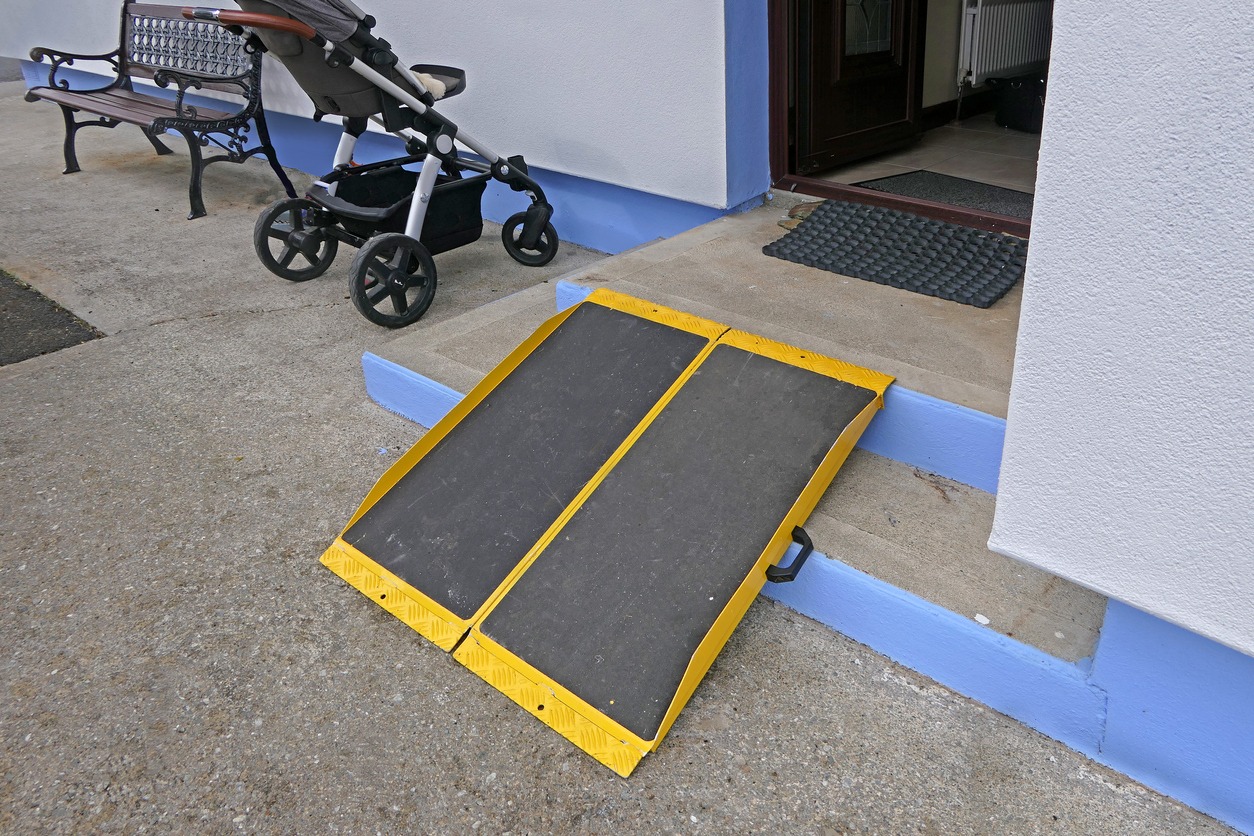 a foldable and portable wheelchair ramp on building’s front steps