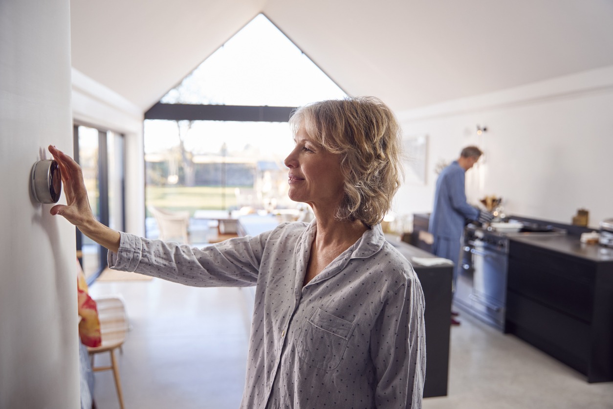 senior woman using a smart thermostat